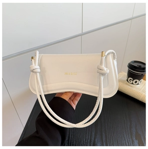 Close-up of a white leather shoulder bag with gold XM & BAGS logo and knotted strap detail