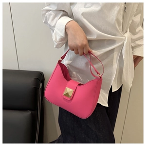 Detail of hot pink crescent bag featuring a prominent gold pyramid-shaped metal buckle