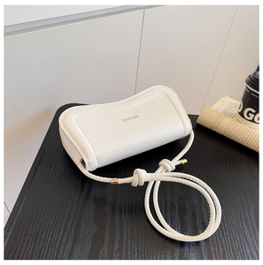 Close-up of white leather crossbody bag with XM & BAGS gold logo and knot strap detail