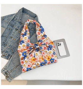 Detail of floral canvas tote bag with daisy prints and large bow knot on white surface