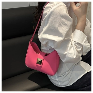 Detailed view of hot pink crescent shoulder bag with gold pyramid stud on white shirt
