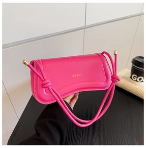 Detail of rose pink matte leather bag with knotted strap and gold hardware accents