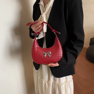 Red half-moon woven shoulder bag with a silver bow and knot strap on a model