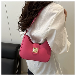 Detailed view of magenta leather hobo bag with a gold pyramid stud on the shoulder strap