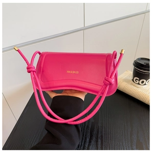 Close-up of fuchsia leather handbag with gold XM & BAGS logo and knotted shoulder strap