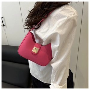 Detail of fuchsia leather crescent bag featuring a prominent gold roman stud accent