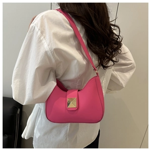Side view of bright pink crescent shoulder bag with golden pyramid buckle on a model