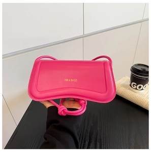 Detail of a bright pink mini crossbody bag with knot shoulder strap and golden logo