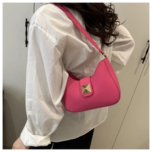 Detail of fuchsia croissant bag with gold studs worn by model in white shirt