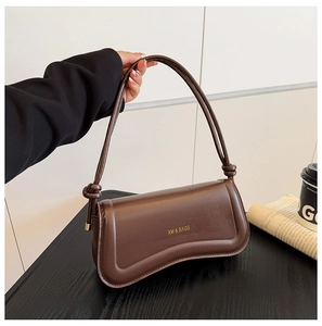 Close-up of a dark brown crescent bag with a knotted strap and gold logo detail