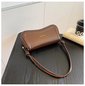 Detail of brown leather handbag with gold logo, knotted shoulder strap and sleek design