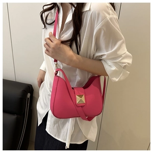 Detail of a magenta crescent shoulder bag with a gold pyramid lock and leather strap
