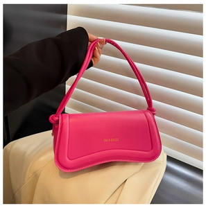 Detail of flamingo pink crossbody bag with unique curved base and gold logo lettering