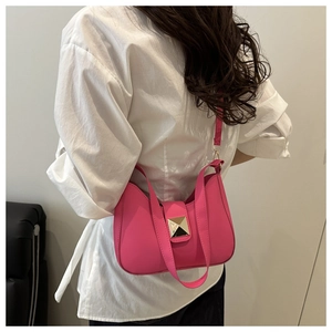 Detailed view of rose pink crescent shoulder bag with a large gold square buckle feature