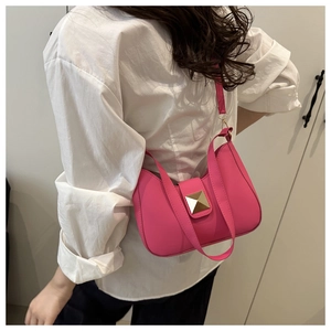 Detailed view of rose pink crescent shoulder bag with gold rivets worn on white shirt