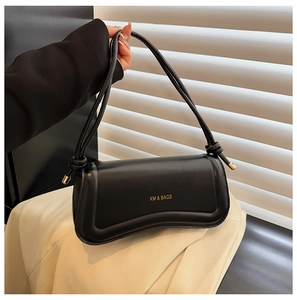 Detail of black baguette bag with gold XM & BAGS logo and knotted shoulder strap