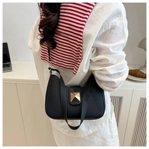Model wearing a black semi-circle shoulder bag with a gold square lock in a lifestyle setting