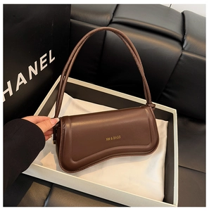Detail of a dark brown leather handbag with a curved base inside a white gift box