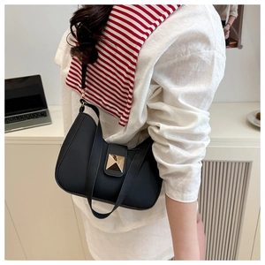 Close-up of minimalist black underarm crescent bag with a gold pyramid metal stud detail