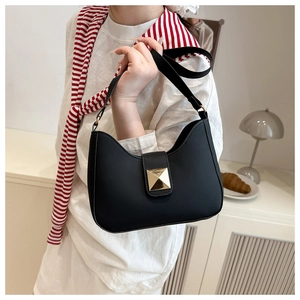 Detail of matte black crescent bag with a gold pyramid stud buckle on the flap