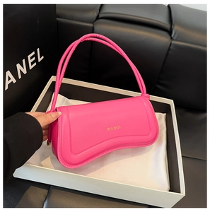 Detail view of fuchsia leather handbag with curved bottom and gold XM & BAGS branding