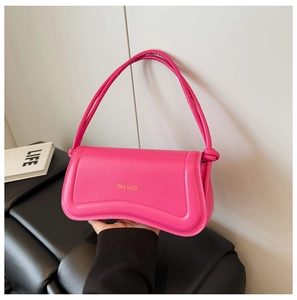 Close-up of bright pink faux leather shoulder bag with knot detail and silver logo