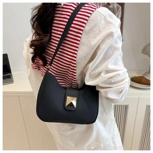 Detail of matte black crescent hobo bag with a prominent gold pyramid metal buckle