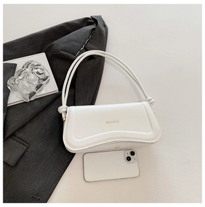 Chic white shoulder bag with wave bottom design and gold logo on textured background