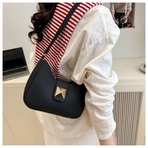 Chic black square shoulder bag with gold pyramid stud on a model's shoulder