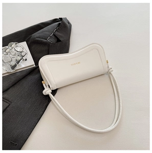 Detail of cream shoulder bag with knot strap and XM & BAGS gold logo lettering