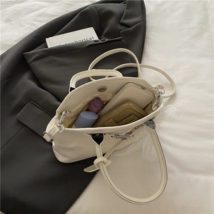 Sac à main rétro beige nacré avec grand espace intérieur posé sur un costume chic