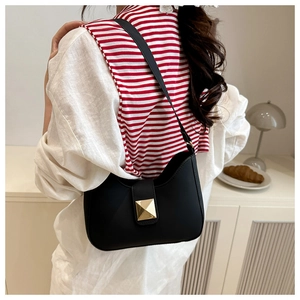 Close-up of black matte leather hobo bag featuring a gold pyramid stud on the magnetic flap