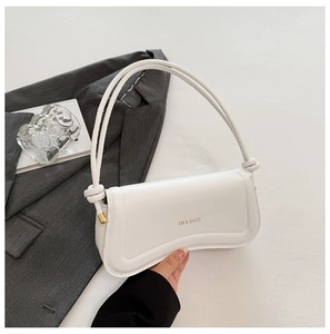 Detailed view of white leather baguette bag with gold XM & BAGS logo and knotted strap