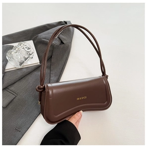 Detailed view of brown faux leather handbag showing knotted strap and gold-stamped logo