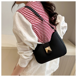 Detail of a black leather hobo bag with a prominent gold square buckle and adjustable strap