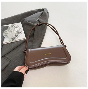 Detail view of coffee brown PU leather shoulder bag with gold XM & BAGS logo on a grey blazer