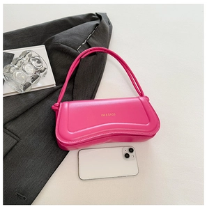 Detail view of pink PU leather shoulder bag with logo next to a suit and smartphone
