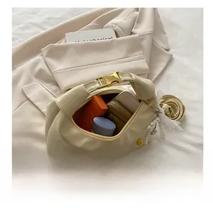 Detail showing spacious interior of beige leather dumpling bag with phone and cosmetics