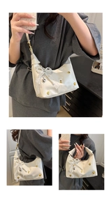 Detail of white leather shoulder bag with lace bow, pearls, and heart pendant decoration
