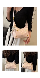 Close-up of pink patent leather half-moon bag with pearl lace bow detail and metal studs