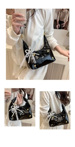 Detail of black glossy shoulder bag featuring pearl bone decor and lace mesh bow detail