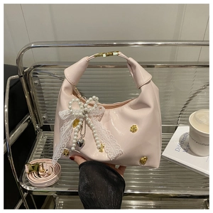 Dettaglio borsa in pelle verniciata rosa con ciondolo a orso d'oro e fiocco di perle chic