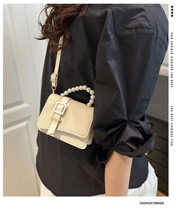Chic cream woven handbag with pearl handle shown as a stylish crossbody bag on a model