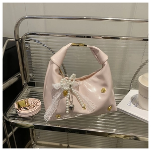Dettaglio borsa hobo rosa chiaro con finiture orsetto oro e ciondolo cuore di perle