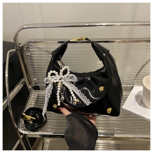 Dettaglio borsa hobo in vernice nera con fiocco di perle e borchie dorate