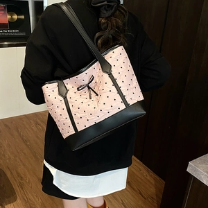 Pink heart print tote bag with black bow and leather handles shown on shoulder