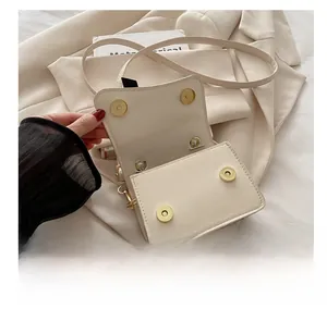 Detail view of the cream PU flap bag showing its dual magnetic snap closure and golden hardware