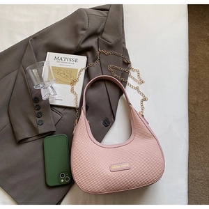 Sac hobo rose tissé avec chaîne dorée présenté sur une veste de blazer grise