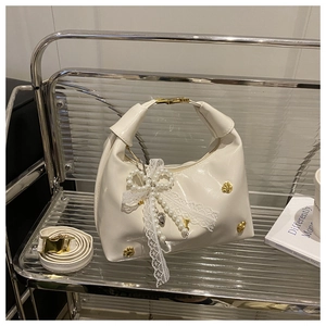 Dettaglio della borsa a mano bianca con fiocco di perle e nastro di pizzo