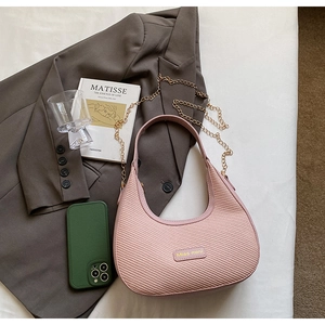 Gros plan d'un sac hobo rose à texture tissée avec chaîne dorée et logo de marque